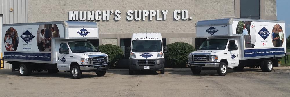 Branded delivery trucks parked outside the Munch's Supply Co. building