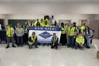 Warehouse crew in safety vests giving a thumbs up at an open loading dock door