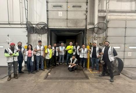 Branch team in safety vests holding a Munch's Supply Now Open banner inside a new location