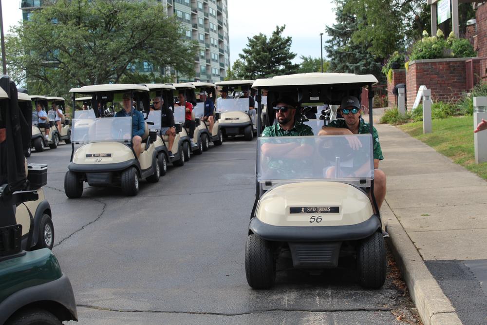 Two golfers smiling from a cart beside the fairway