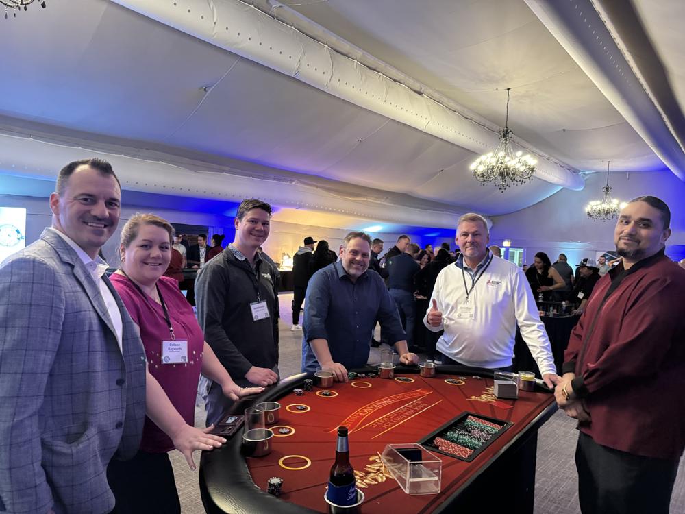 Group of contractors and vendor partners standing around a card table at the dealer meeting